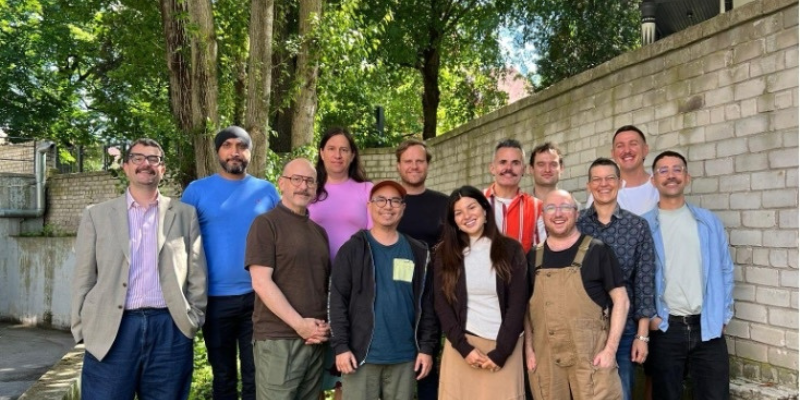 Group photo of participants from the LGBTI Pathways program gathered outdoors in Tallinn, standing together in front of trees and a brick wall.